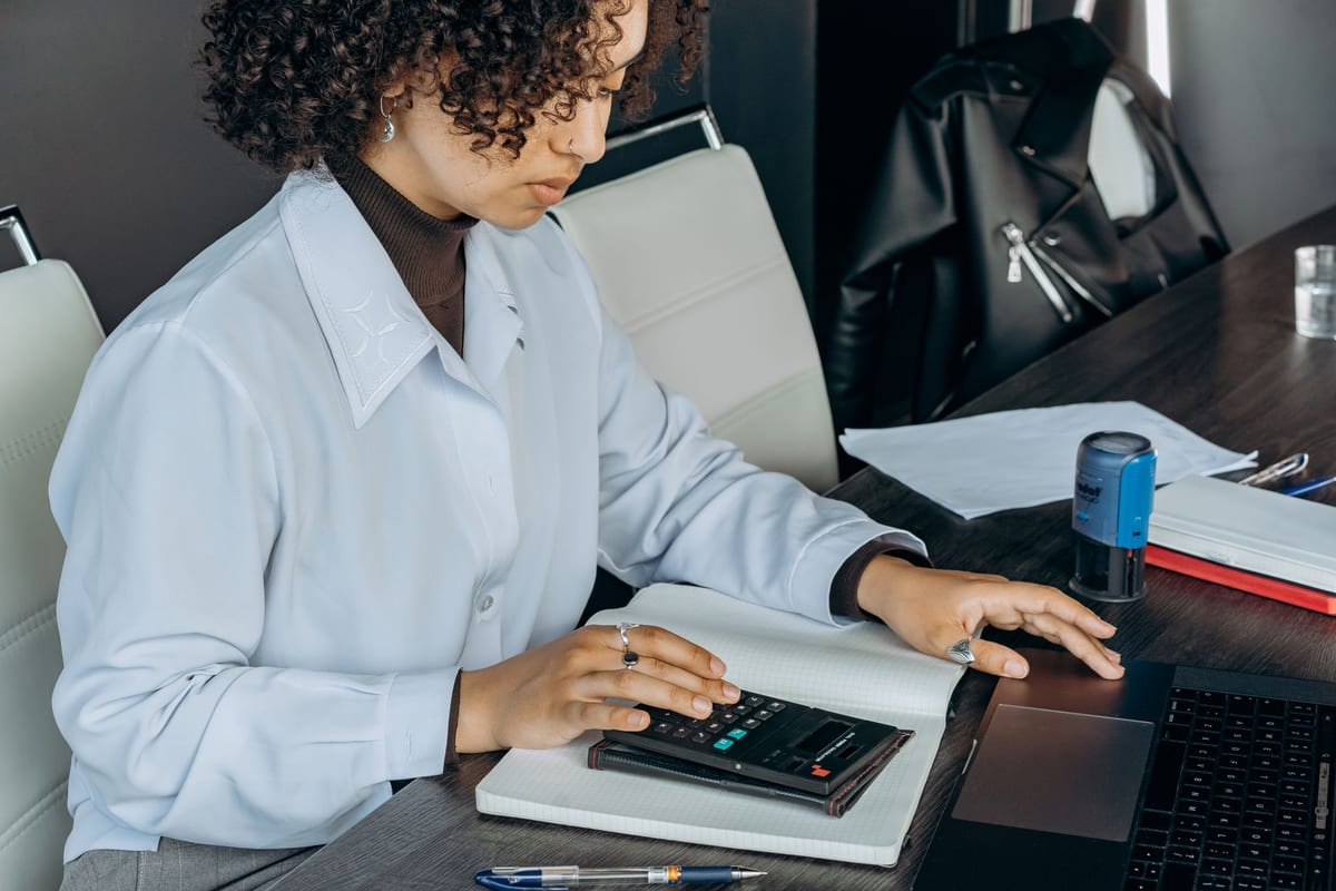 A bookkeeper working through entries with a calculator at a desk