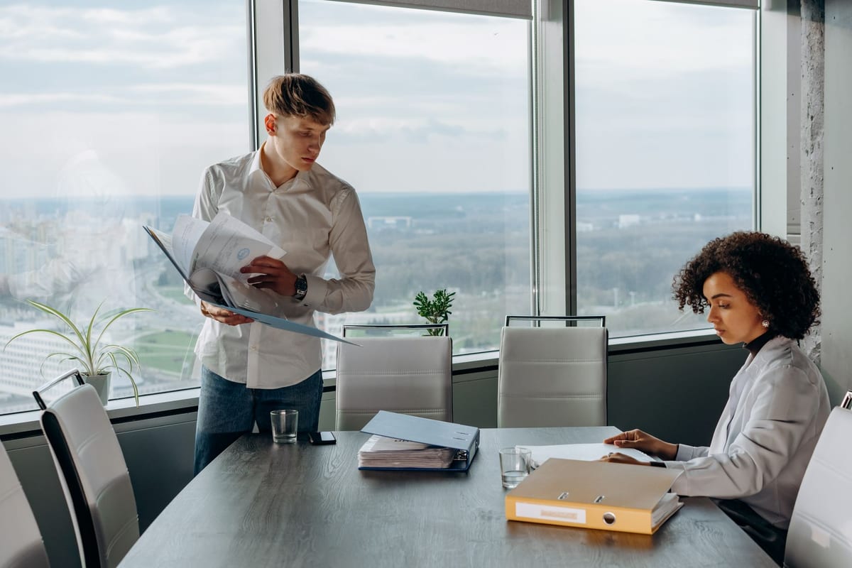 Two colleagues going over documents in a boardroom with a view