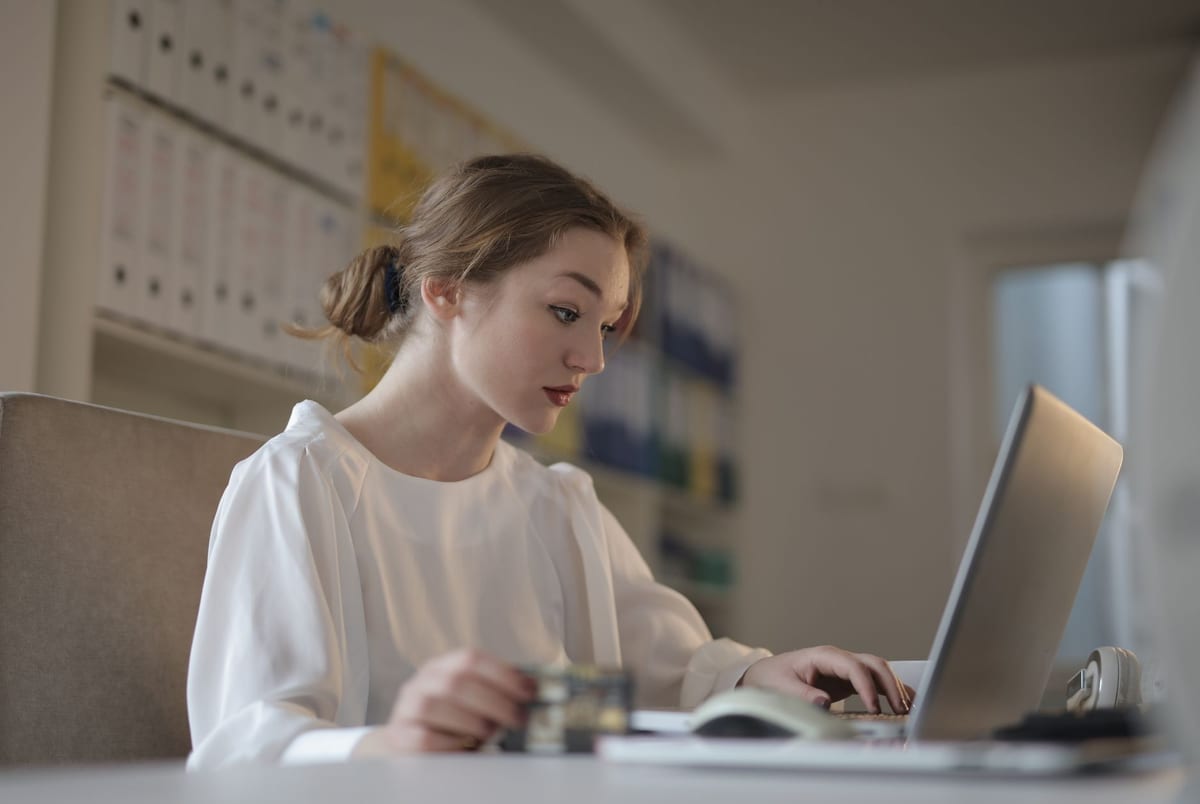 An accountant entering payroll on a laptop in a bright office
