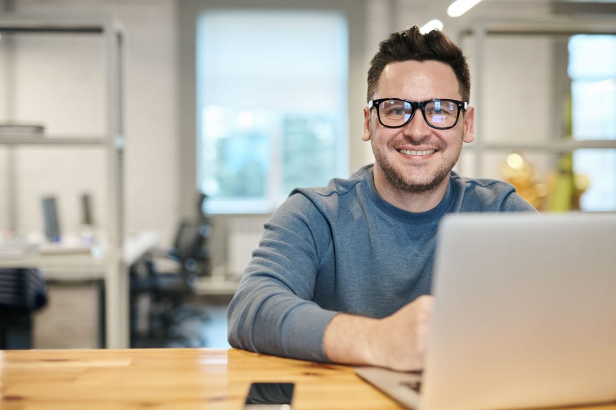 A self-employed professional working at a laptop in a bright open office